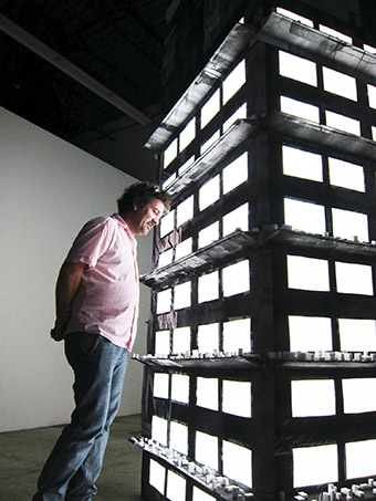 Dimensions Variable gallery , artist Candelario listening to his installation tower, Personal Luggage.