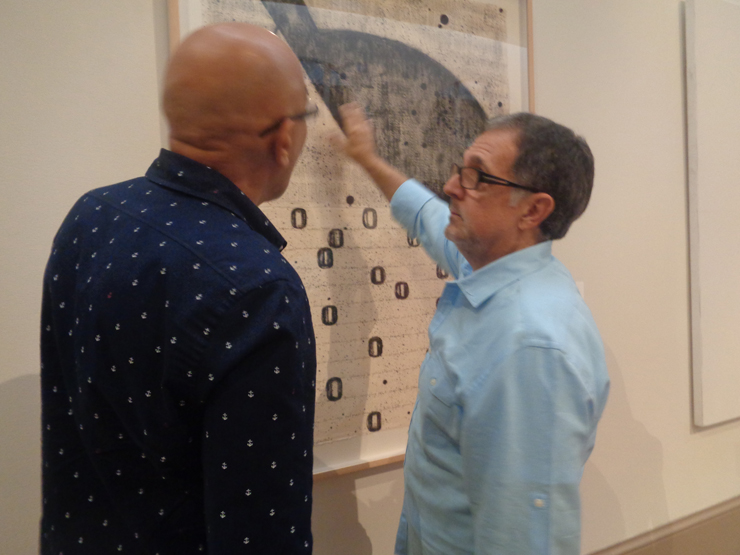 Artist Mario Bencomo explaining some of the features included in his work to a guest during the opening.