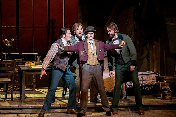 The supporting bohemians are bass Simon Dyer as the philosopher Colline and baritone Benjamin Dickerson as the feisty top-hatted musician Schaunard, shown with Treveor Schenemann as Marcello and Alesandro Scotto di Luzio as Rodolfo. Photographer: Chris Kakol