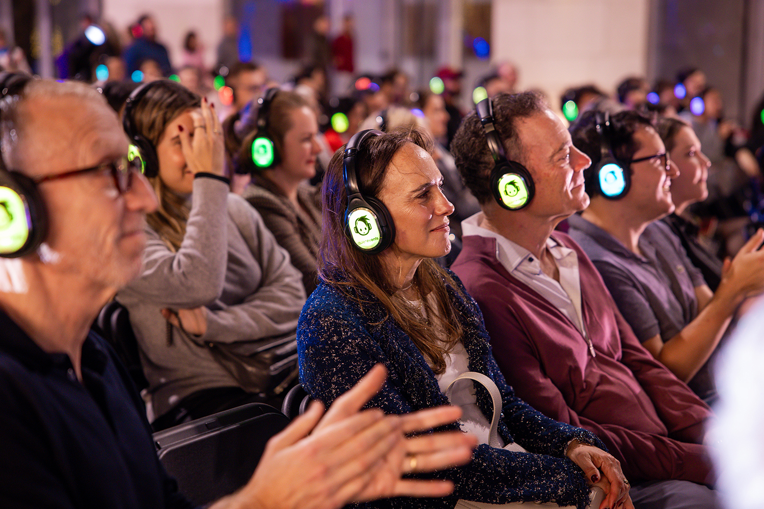 Audience members wear color coded headphones for
