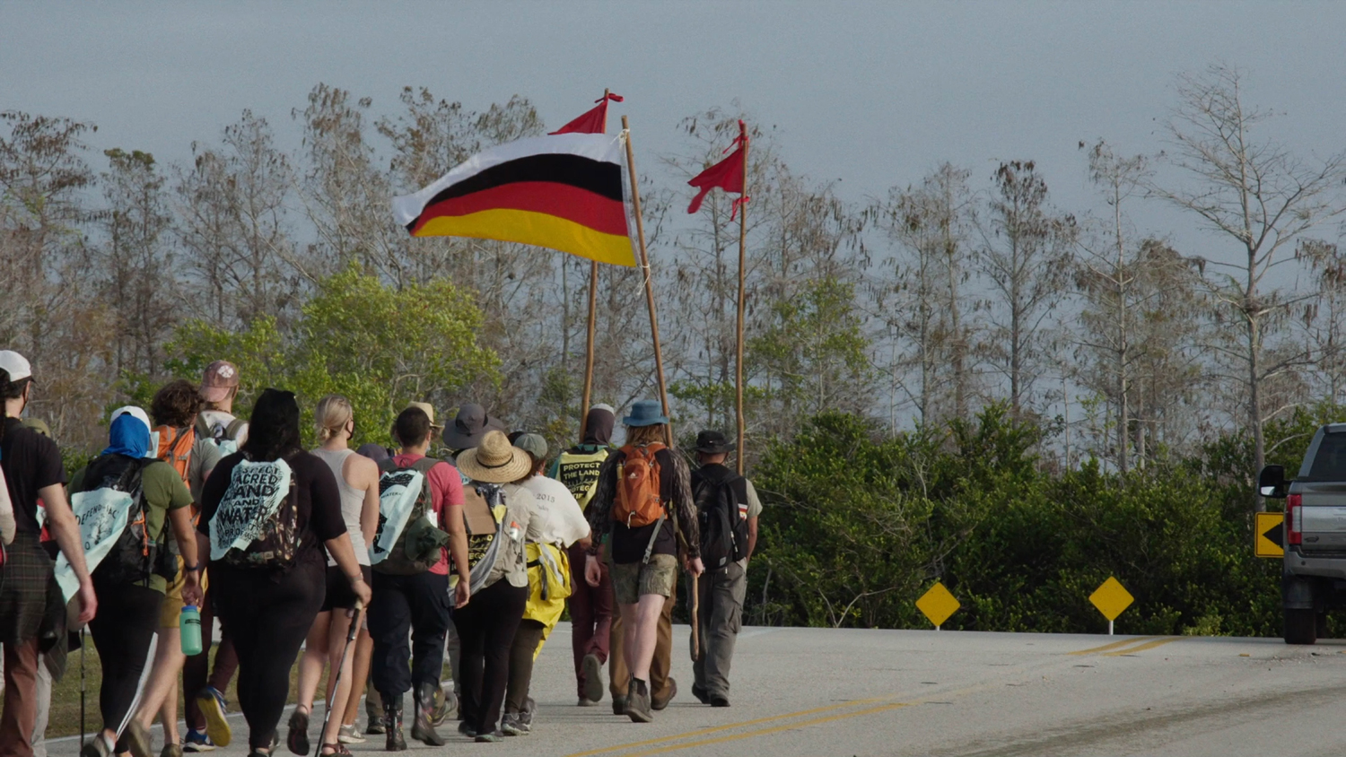 Prayer walkers carrying a Miccosukee flag in the documentary