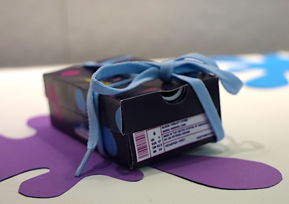 Tyriana White presents her mock-up packaging design for a fictional shoe customization brand, showing her focus on product branding and visual identity. (Photo by Marlee Card)