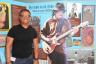 Mexican State News Agency Correspondent Pablo Tonini poses next to Carlos Santana display